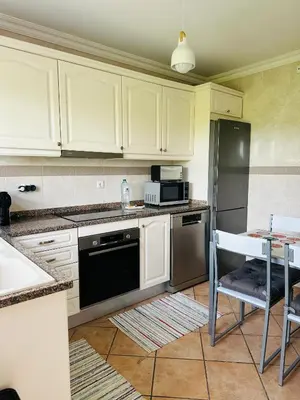 a kitchen with white cabinets and a black refrigerator at Casa Esperança in Albufeira