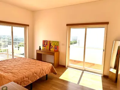 a bedroom with a bed and two large windows at Vila Elvia in Albufeira