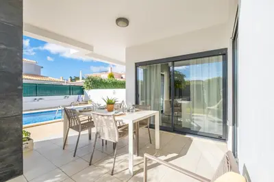a dining room with a table and chairs on a patio at Villas Novochoro - Small Garden by DreamvillasAlbufeira in Albufeira