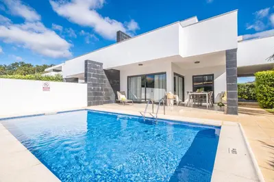 a villa with a swimming pool in front of a house at Villas Novochoro - Small Garden by DreamvillasAlbufeira in Albufeira