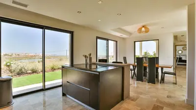 an open kitchen and dining room with large windows at Brand New Waterfront Villa with pool in Faro