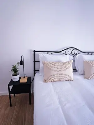 a white bed with white pillows and a table with a plant at Carmo City Center 2 in Faro
