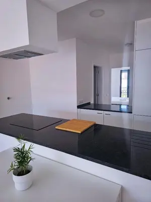 a white kitchen with a black counter top at Carmo City Center 2 in Faro