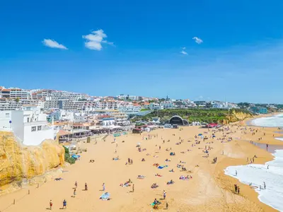 a group of people on a beach near the ocean at Casa na Muralha - Beach front - Rooftop Jacuzzi by DreamvillasAlbufeira in Albufeira