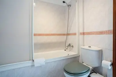 a bathroom with a shower and a toilet and a tub at Blife Allya private rooms in Faro