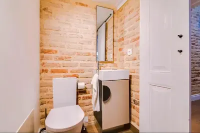 a bathroom with a white toilet and a brick wall at Blife Frankya private rooms in Faro
