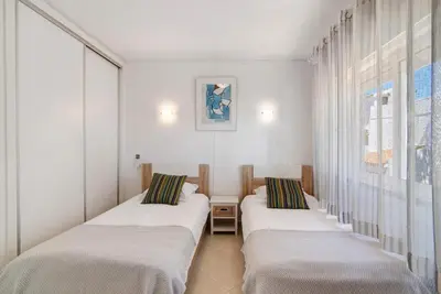 two beds in a room with white walls and a window at Townhouse Ramas in Vale do Lobo