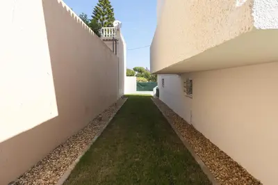 an alleyway between two white buildings with grass at Vila Branca - V3 by HD PROPERTIES in Quarteira