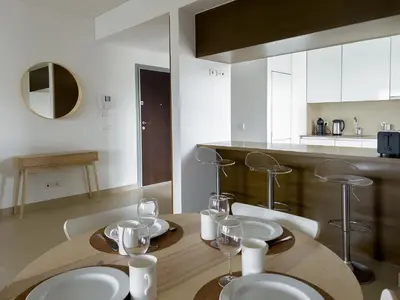 a kitchen with a wooden table with plates and wine glasses at Стильный апартамент Т2 Quarteira in Quarteira