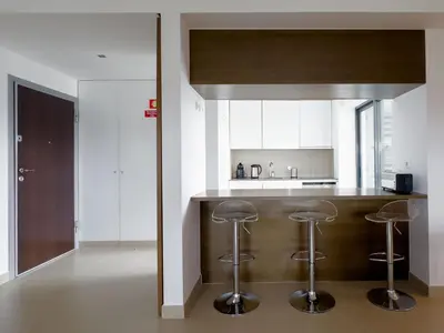a kitchen with a wooden counter and stools at Стильный апартамент Т2 Quarteira in Quarteira