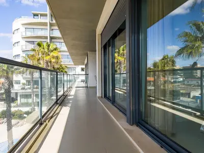 an internal corridor of a building with large windows at Стильный апартамент Т2 Quarteira in Quarteira