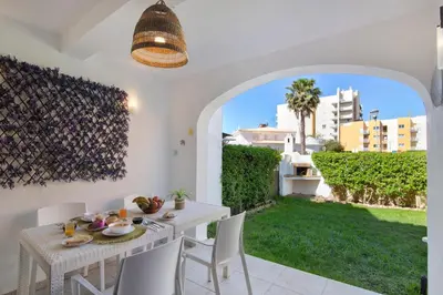 a dining room with a table and chairs and a view of a yard at Casa Sol in Quarteira