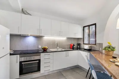 a kitchen with white cabinets and a sink and a counter at Casa Sol in Quarteira