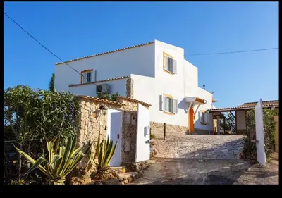a white house with a door and some plants at Blife Moustachya private rooms in Faro