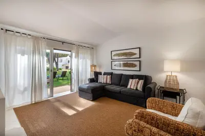 a living room with a couch and a table and chairs at Vilamouratenis Wave by SAPvillas in Vilamoura