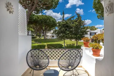 a wooden table and chairs with an umbrella at Albufeira Balaia Golf Vilage 5 With Pool by Homing in Albufeira