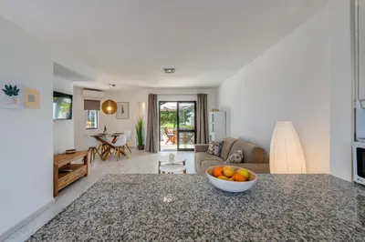 a kitchen and living room with a bowl of fruit on a counter at Albufeira Balaia Golf Vilage 5 With Pool by Homing in Albufeira