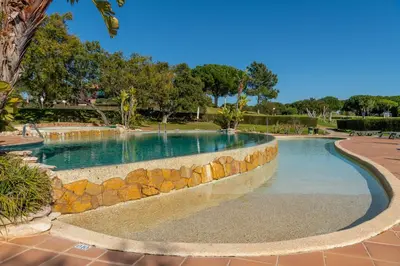 a swimming pool with a stone wall around it at Albufeira Balaia Golf Vilage 6 With Pool by Homing in Albufeira