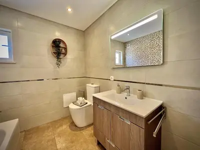 a bathroom with a tub and a tiled wall at Albufeira Balaia Golf Vilage 6 With Pool by Homing in Albufeira