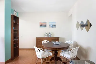 a dining room with a wooden table and white chairs at Apartamento Sunny in Quarteira