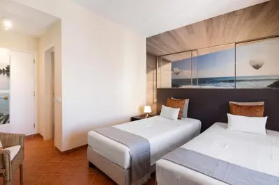 a hotel room with two beds and a chair at Apartamento Sunny in Quarteira