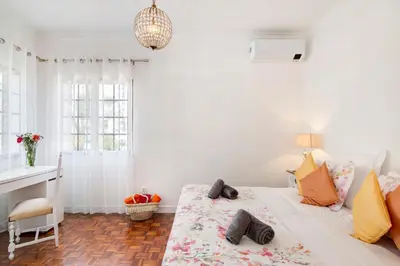 a white bedroom with a bed with a floral bedspread at Sunshine House in Faro