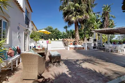 a patio with chairs and tables and palm trees at Country House Quinta da Ilda in Loulé