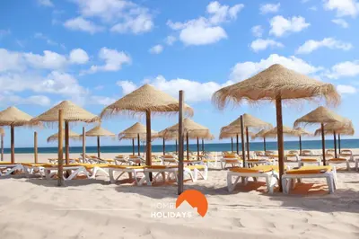 a beach with chairs and umbrellas on the sand at #268 Marvellous Villa Sapphire in Albufeira
