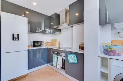 a kitchen with white cabinets and blue appliances at Downtown Bingo Apartment in Faro