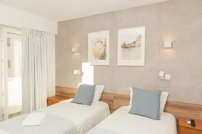 a bedroom with two beds with white and blue pillows at Faro Heart Suites in Faro