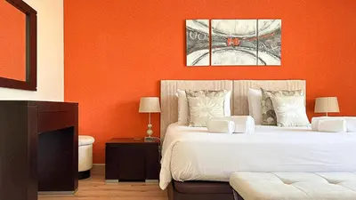 a bedroom with two beds and an orange wall at Vista Marina Exclusiva T1 HsR Vilamarina in Quarteira