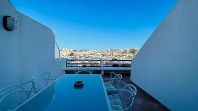 a balcony with a table and chairs and a view of a city at Penthouse Triplex Marina T2 by HsR Vilamarina in Quarteira