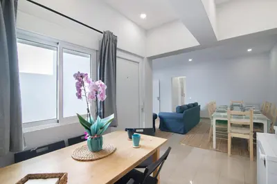 a dining room and living room with a table with flowers on it at Skipper House in Loulé