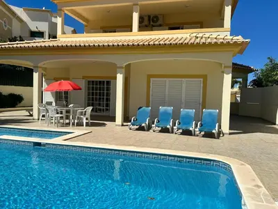 a house with a swimming pool with chairs and a table at Benvindo Villa by Umbral in Albufeira