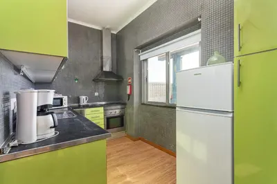 a kitchen with a white refrigerator and green walls at Blife Bandaya private apartment in Faro