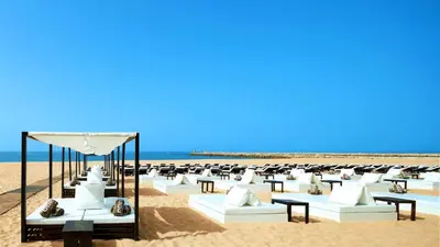 a beach with white couches and chairs on the sand at Lotus by Check-in Portugal in Quarteira