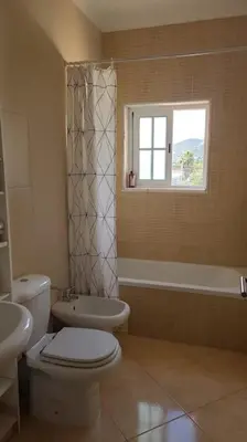 a bathroom with a toilet and a sink and a window at Stela ' s Guest House in Loulé