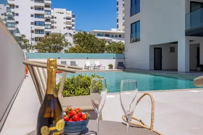 a table with a bottle of wine and a bowl of fruit next to a pool at Terracos de Quarteira Blue by Real Properties in Quarteira