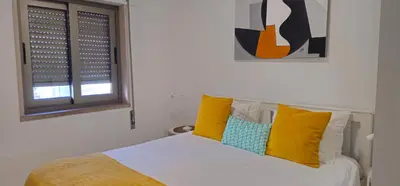 a bedroom with a bed with yellow and blue pillows at Casa dos Sinos 2Bedroom Beach Apartment with Terrace in Albufeira