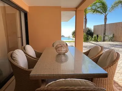 a table with chairs and a vase on top of it at Villa Oceânica in Albufeira