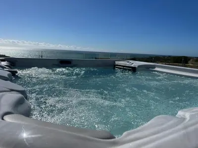 a hot tub with water in it next to the ocean at Villa Oceânica in Albufeira