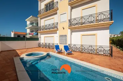 a house with a swimming pool and two blue chairs at #228 Garrett Flats by Home Holidays in Albufeira