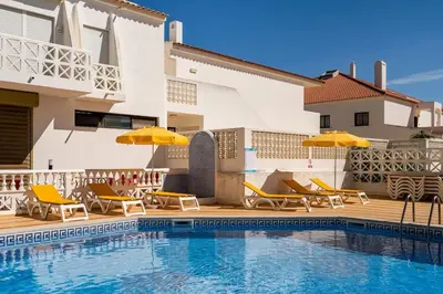 a pool with chairs and umbrellas next to a house at OURA WHITE VIEW Beach 2 min walk sea in Albufeira