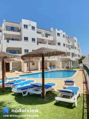 a pool with chairs and umbrellas in front of a building at Silmaria Sea View amazing in Albufeira
