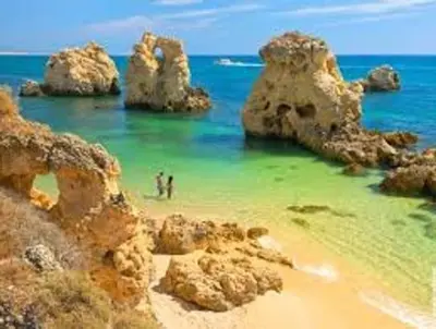 a person standing in the water on a beach with rocks at Silmaria Sea View amazing in Albufeira
