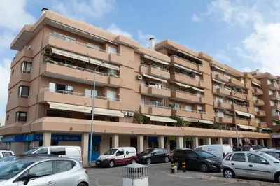 a large building with cars parked in a parking lot at Blife Ricardya private rooms in Faro