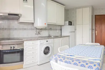 a kitchen with white cabinets and a washer and dryer at Blife Ricardya private rooms in Faro