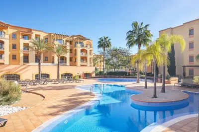 a swimming pool with palm trees and buildings at The Residences Vilamoura, Apartment Melissa in Vilamoura