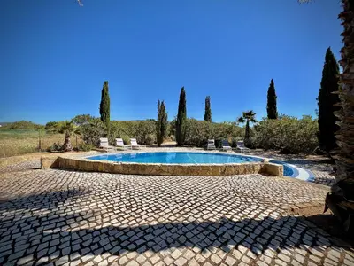 a swimming pool with chairs and trees in the background at Quarteira Premium Villa With Pool by Homing in Quarteira
