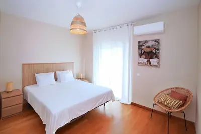 a bedroom with a white bed and a chair at Casa Santos in Albufeira